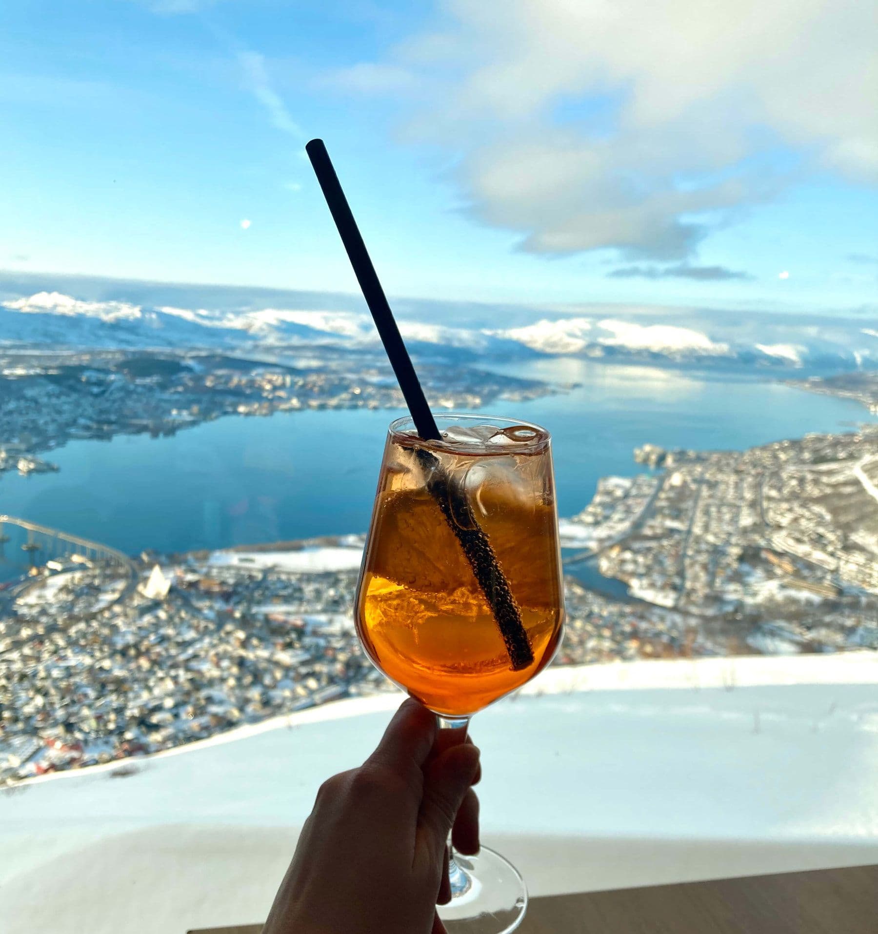 Sklenice s drinkem nad panoramatem města a fjordu